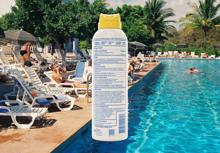Sunscreen spray bottle with a pool and beach chairs in the background