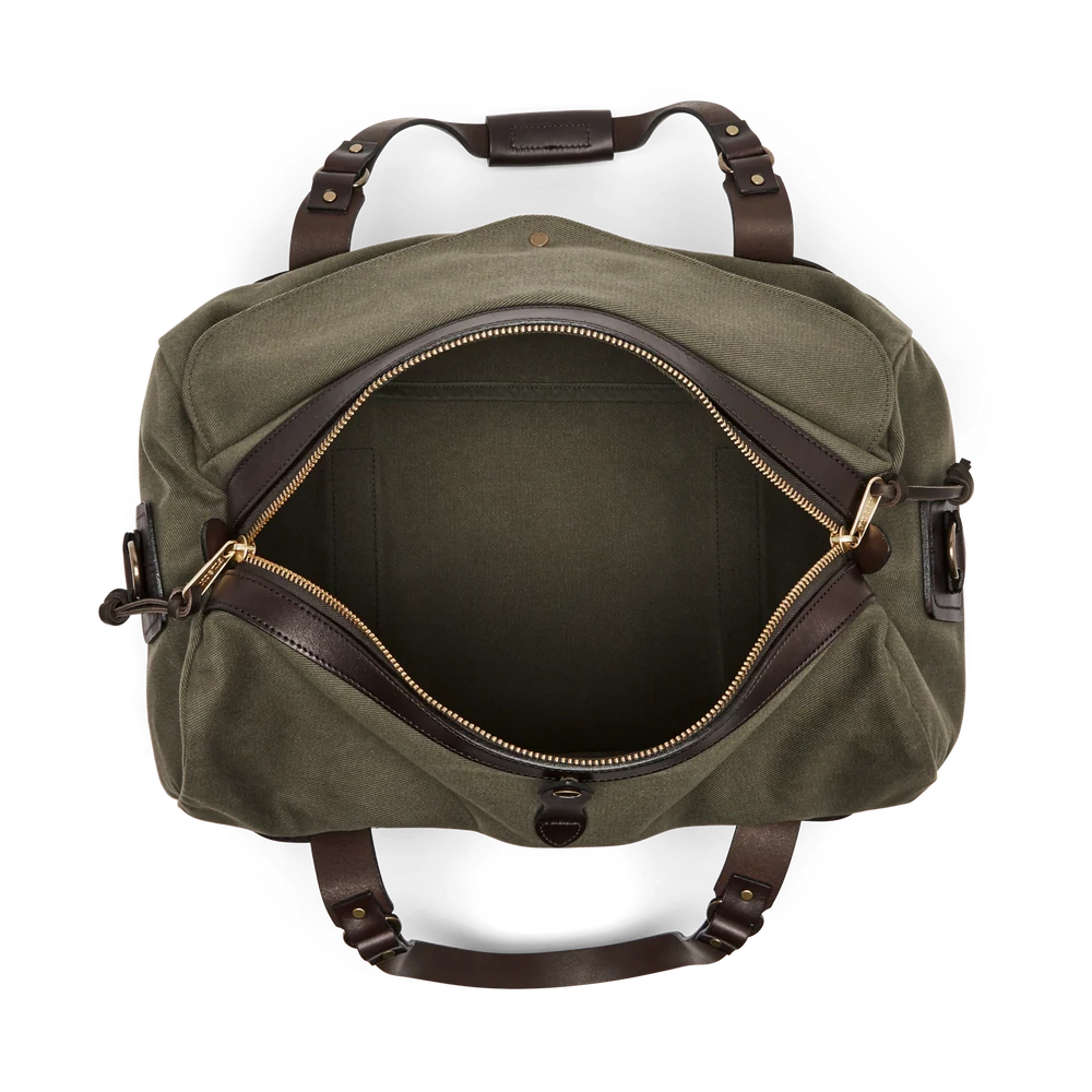 An olive green canvas duffel bag with dark brown leather handles and trim, shown open to reveal its interior. The bag is photographed from a top-down perspective on a clean white background.