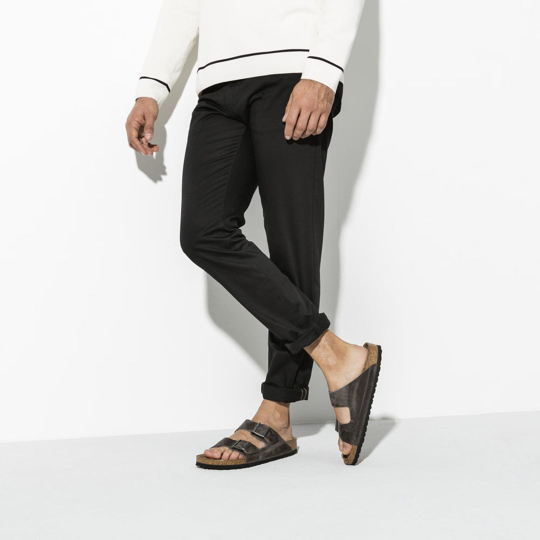 Person wearing black pants and sandals on a white background