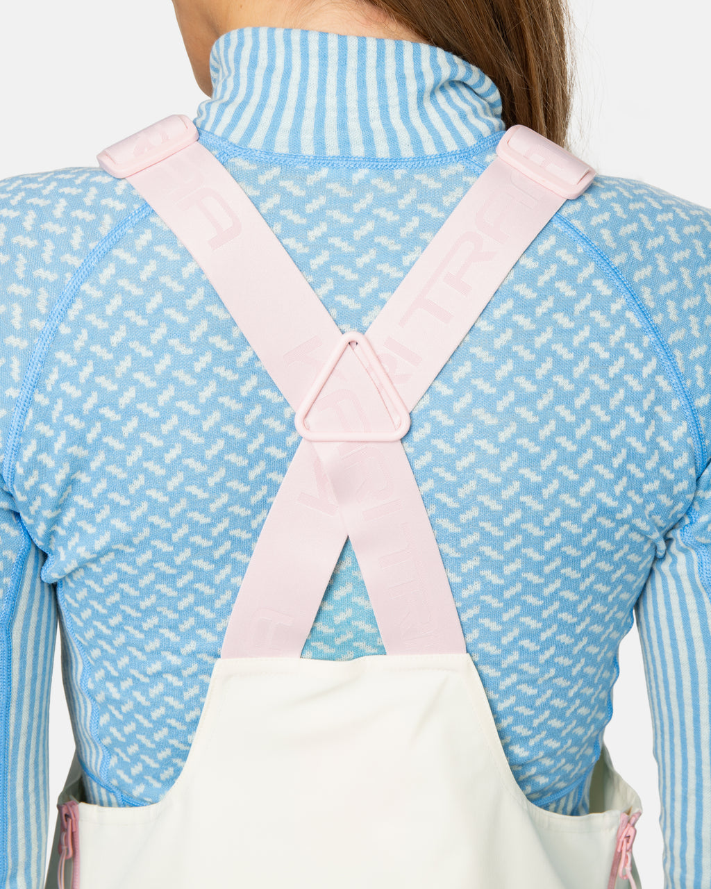 Person wearing a white apron over a blue outfit with a pink zipper.