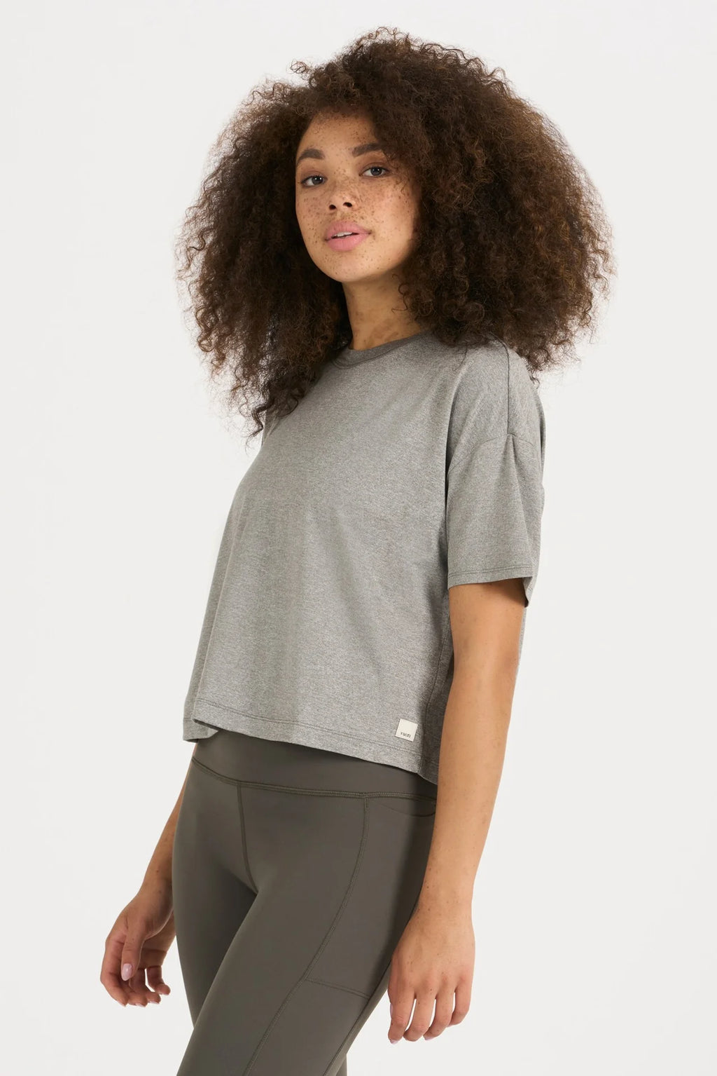 Woman wearing a gray t-shirt and dark pants on a white background