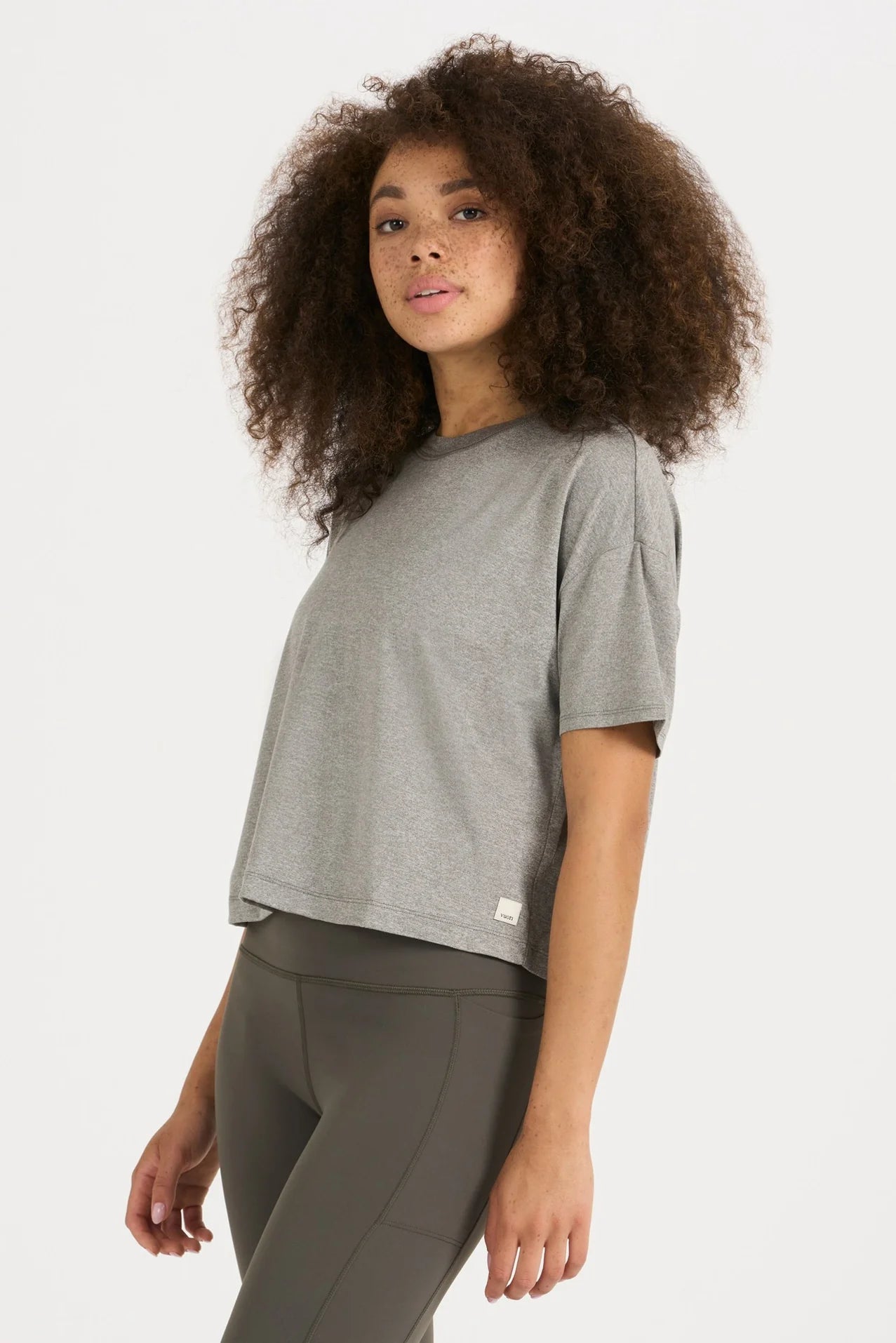 Woman wearing a gray t-shirt and dark pants on a white background