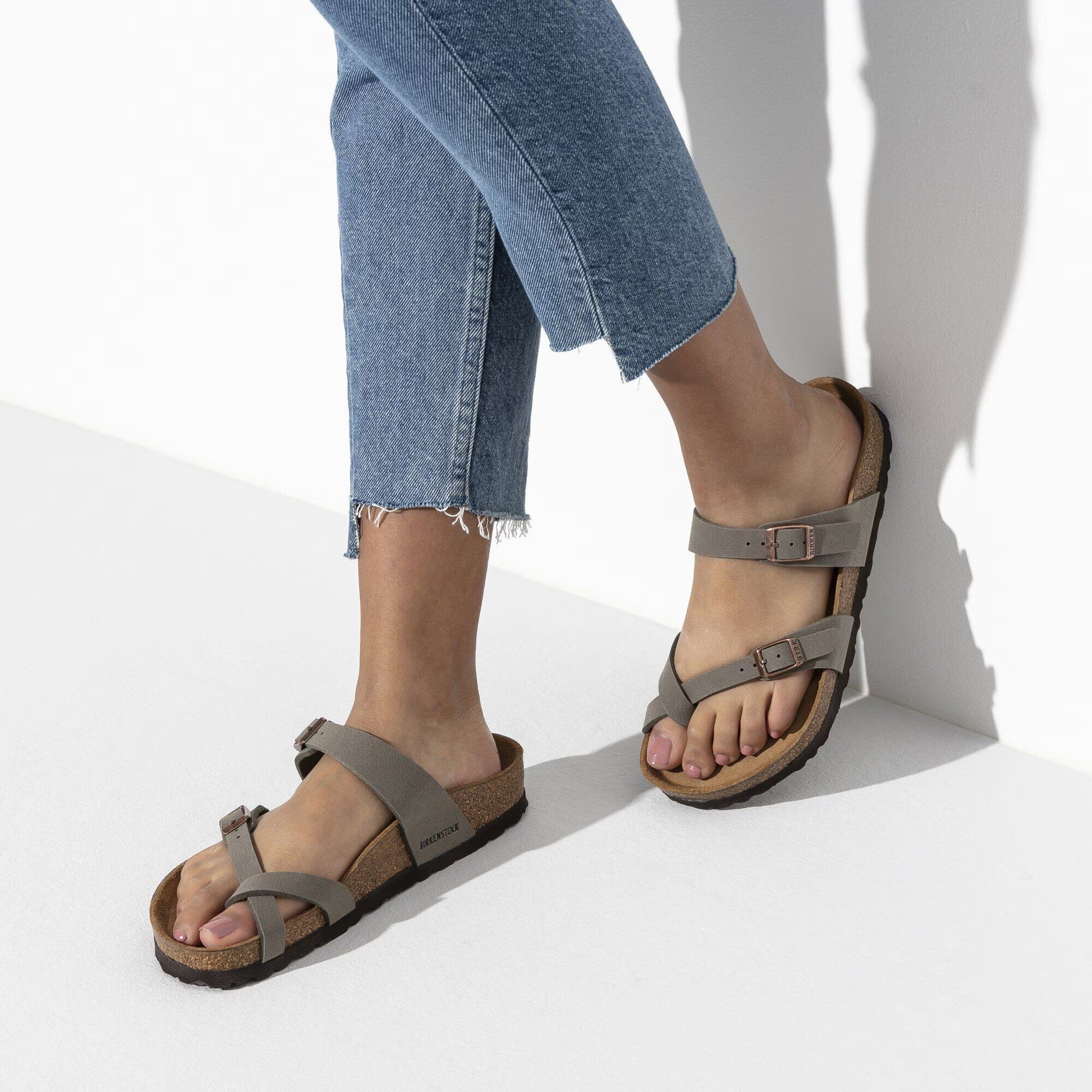 Person wearing gray sandals with a white background