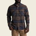 Man wearing a plaid shirt and beige pants on a white background