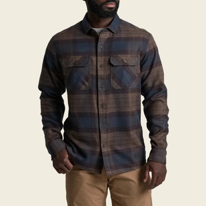 Man wearing a plaid shirt and beige pants on a white background