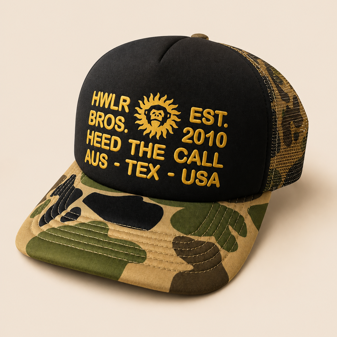 A black and camouflage trucker cap with yellow embroidered text and a sun logo on the front, set against a solid beige background.