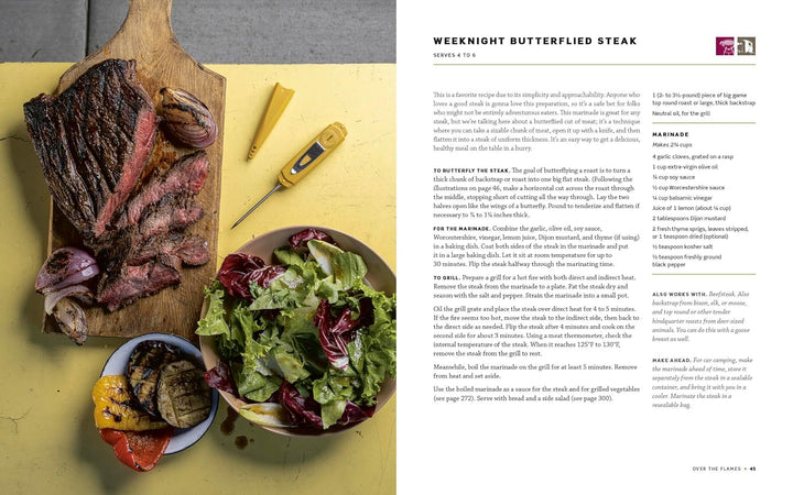Steak on a cutting board with a side of salad and vegetables on a yellow surface, next to a magazine article.