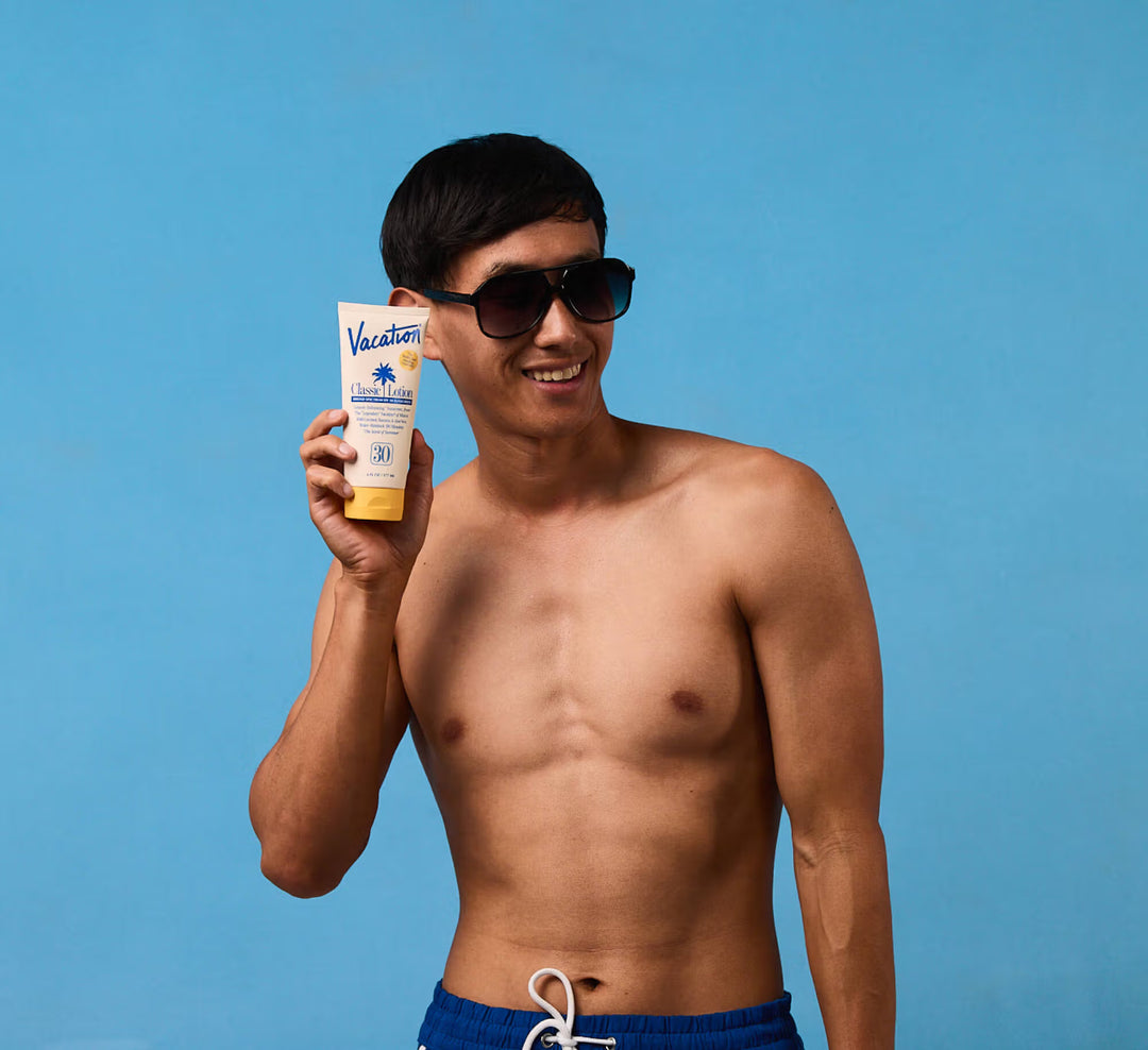 Man holding a sunscreen bottle with a blue background