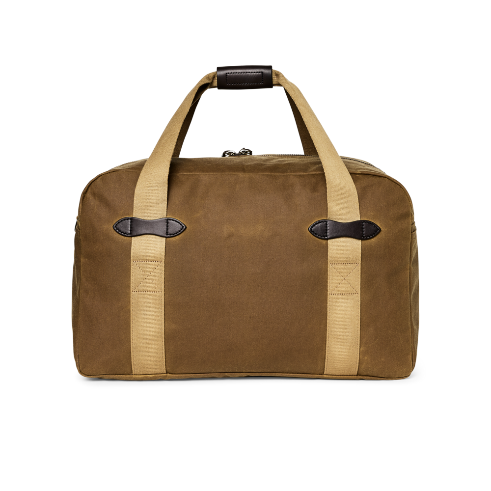 A brown waxed canvas duffel bag with beige webbing handles and trim, featuring dark brown leather accents on the handles and side straps, shown against a plain white background.