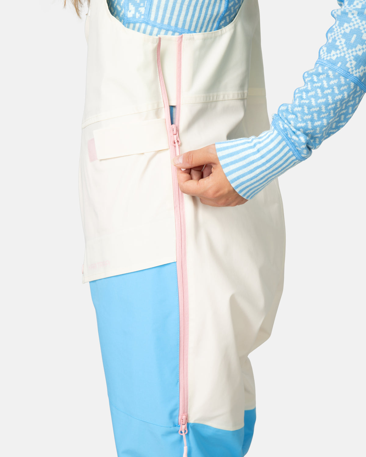 Person wearing a white apron over a blue outfit with a pink zipper.