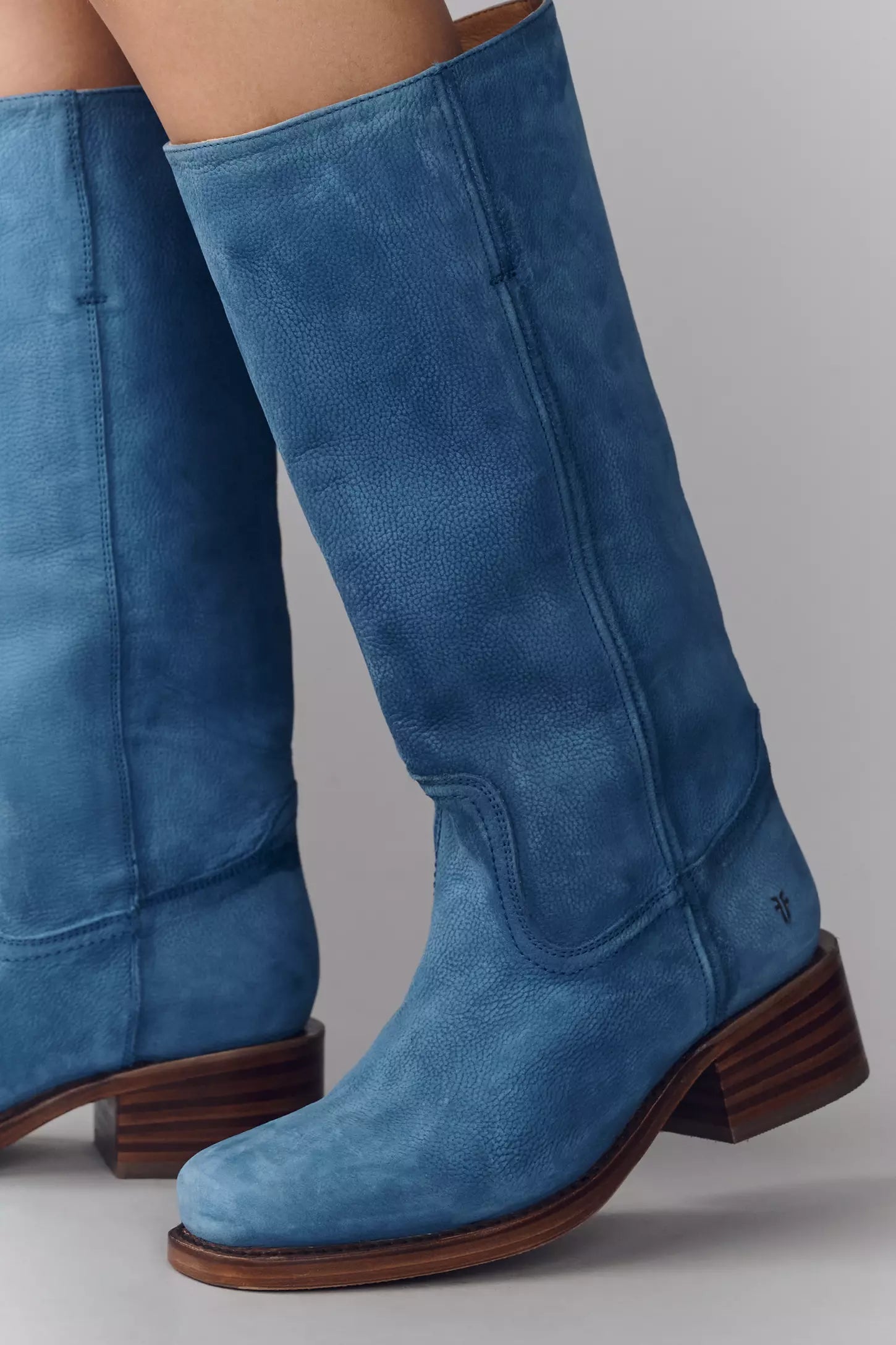 Blue knee-high boots with brown soles on a gray background