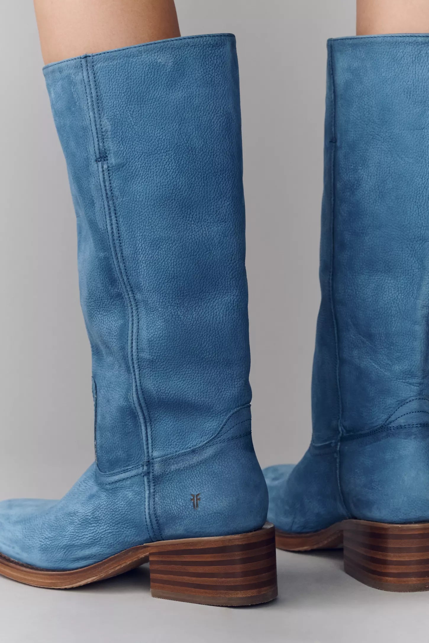 Blue suede knee-high boots on a gray background