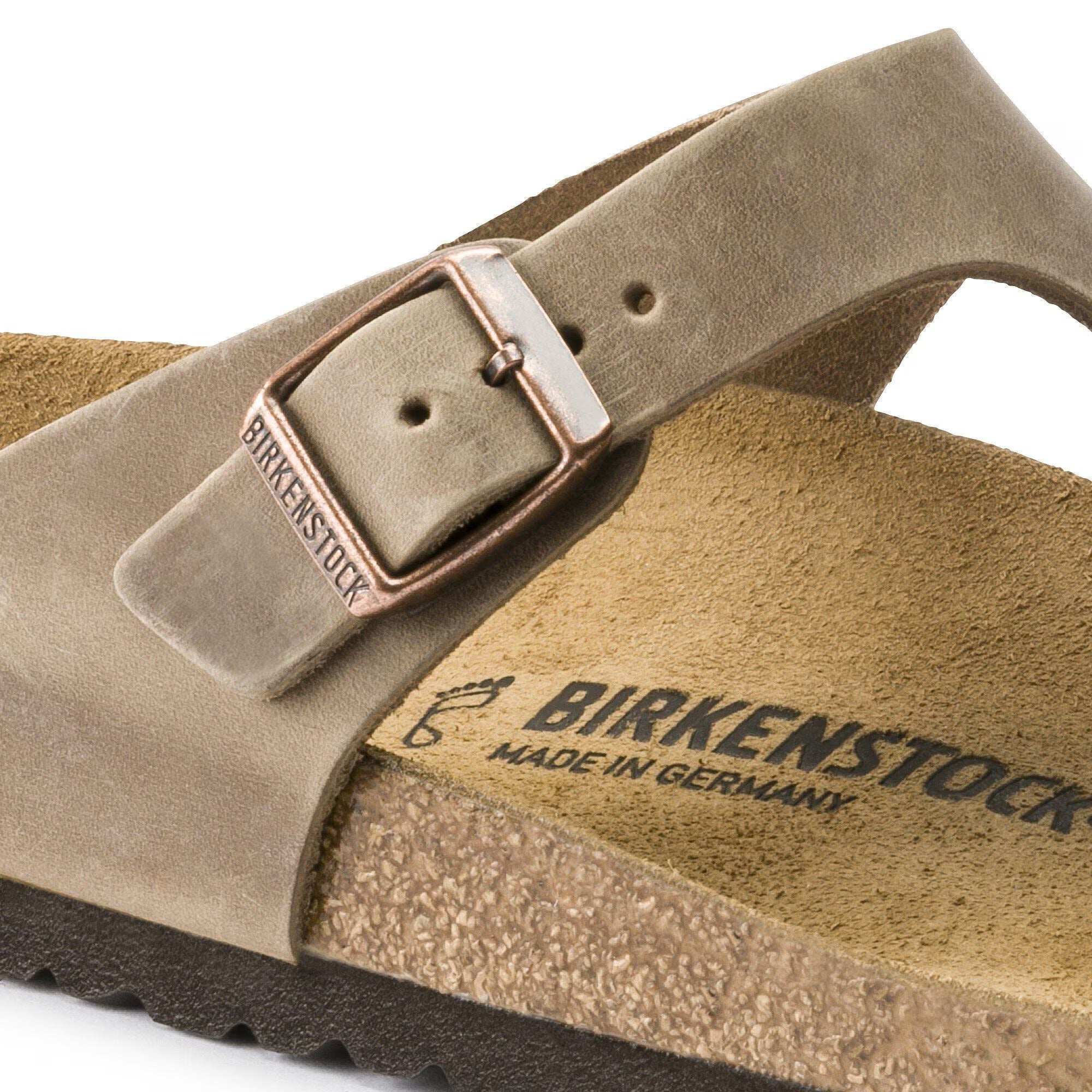 Brown sandal with a buckle and 'Birkenstock' branding on a white background