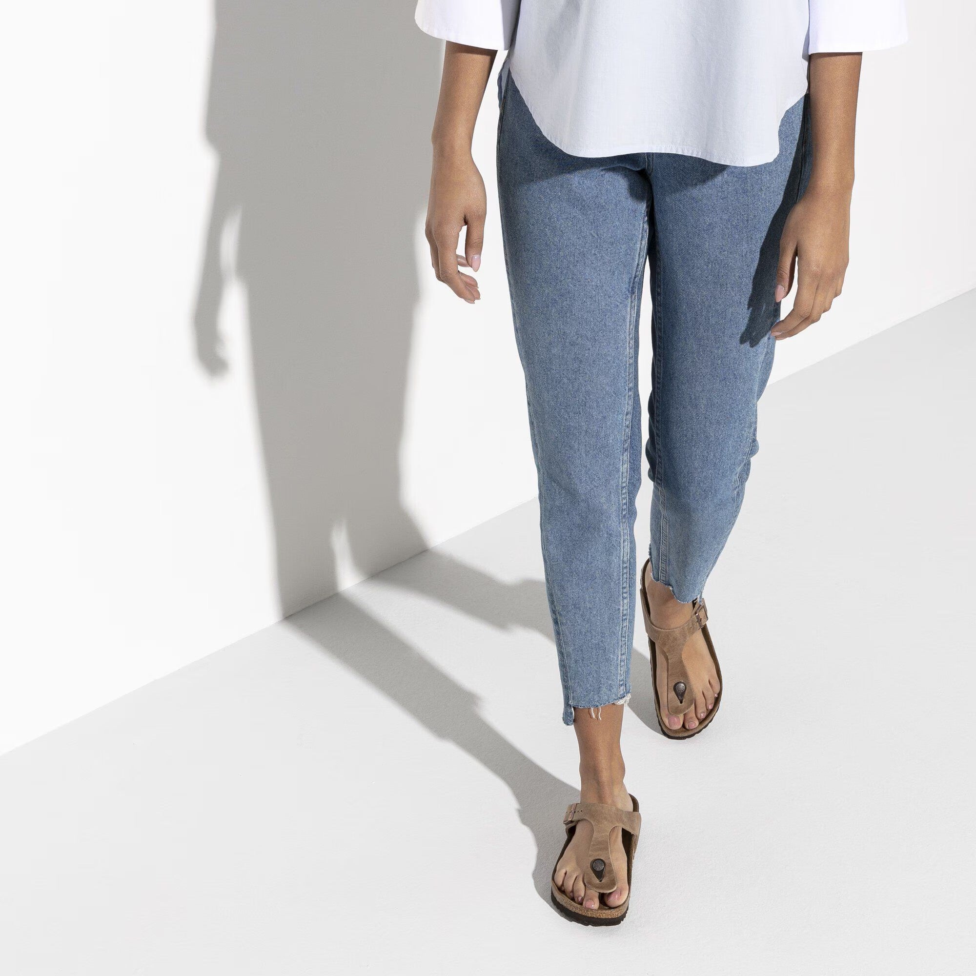 Person wearing blue jeans and a white top on a white background