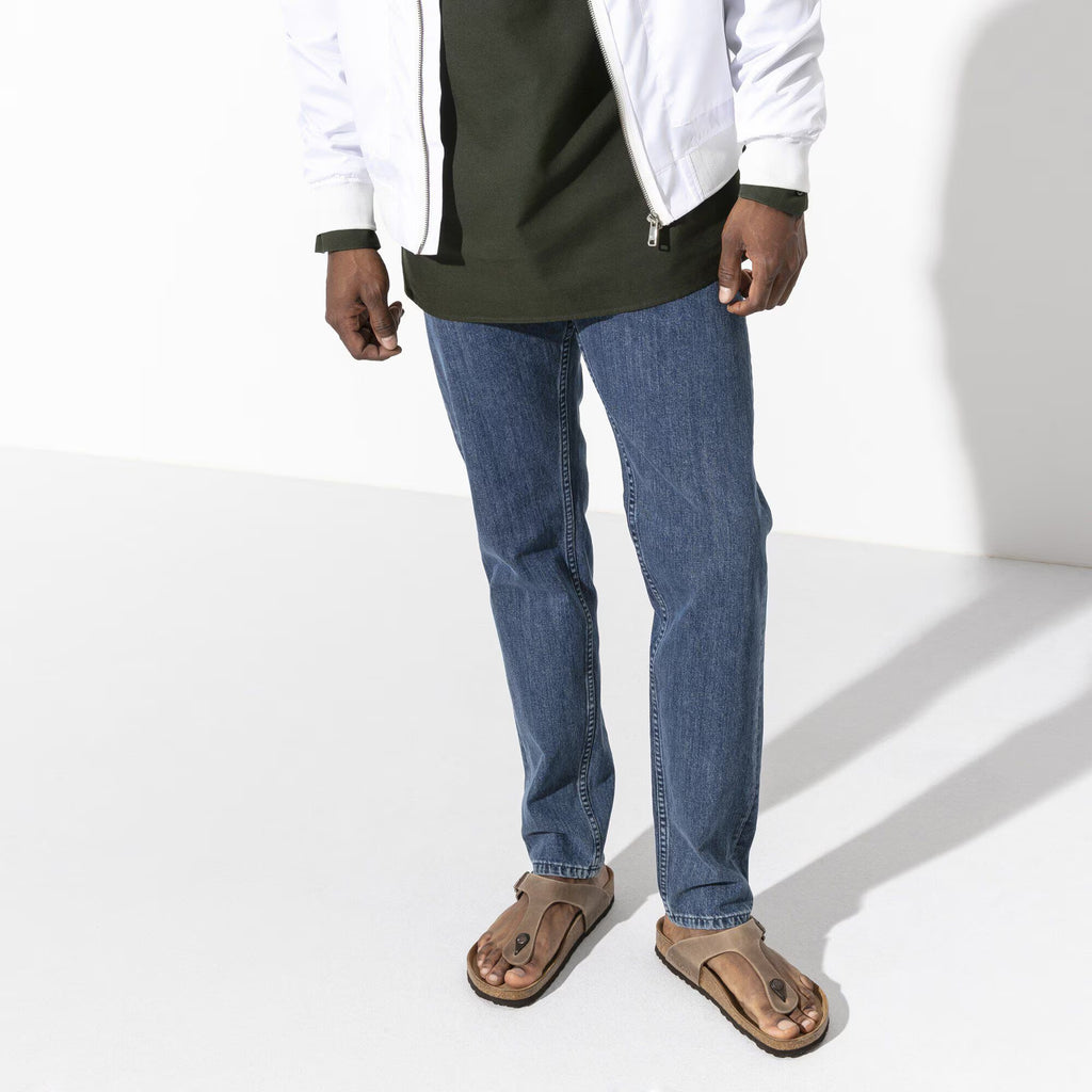Person wearing blue jeans and a white jacket on a white background
