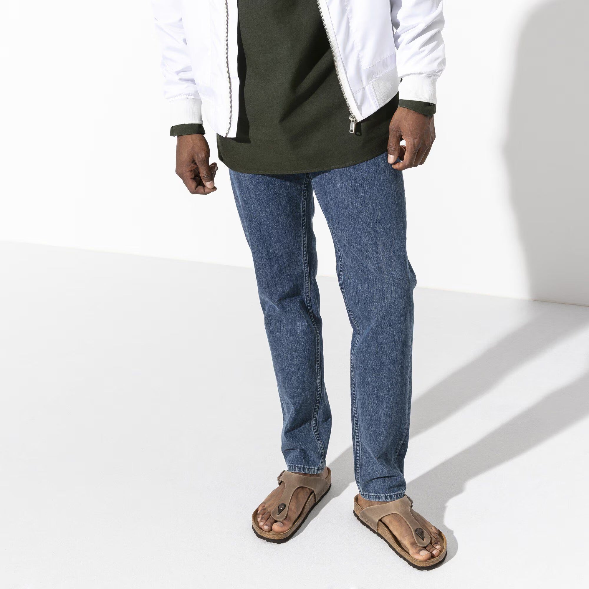 Person wearing blue jeans and a white jacket on a white background