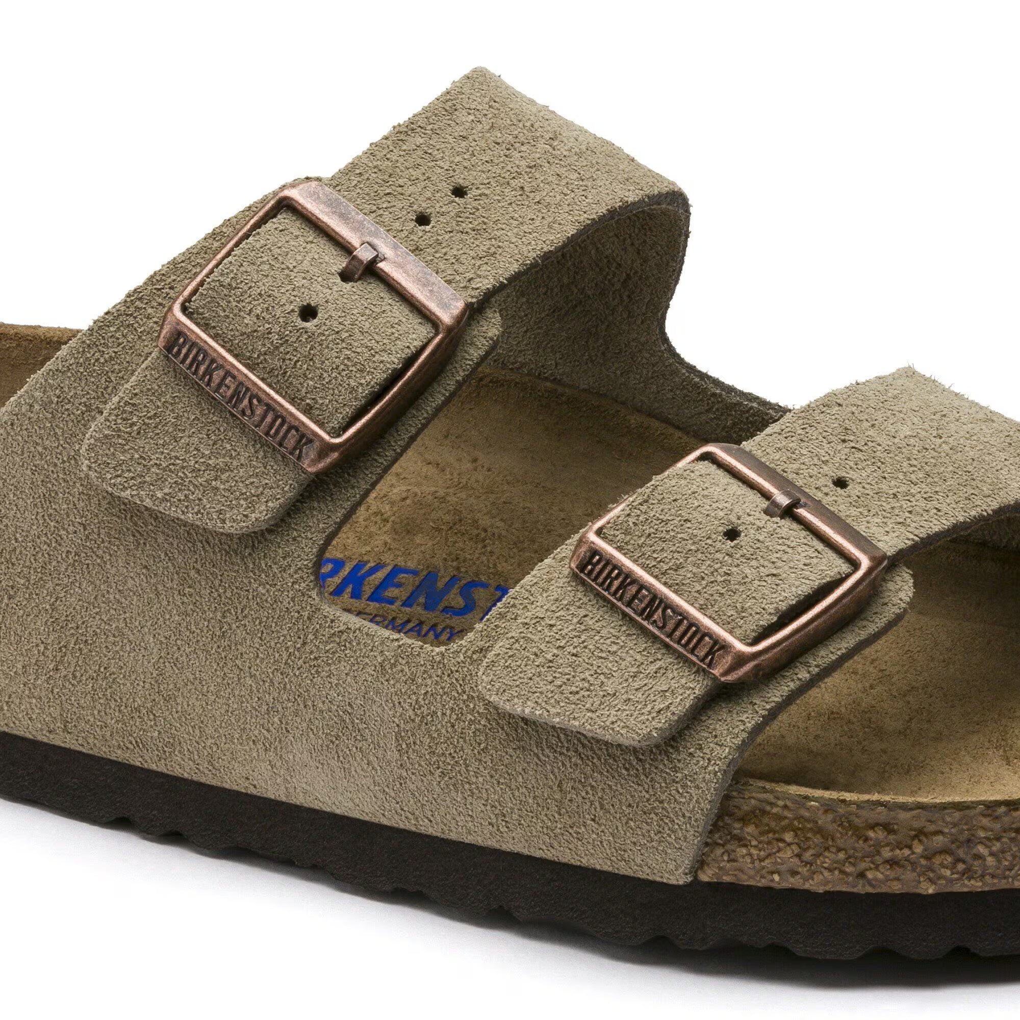 Brown sandal with copper buckles on a white background