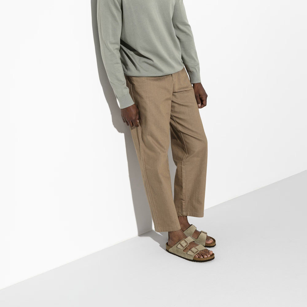 Brown sandal with double buckle on a white background worn by a man