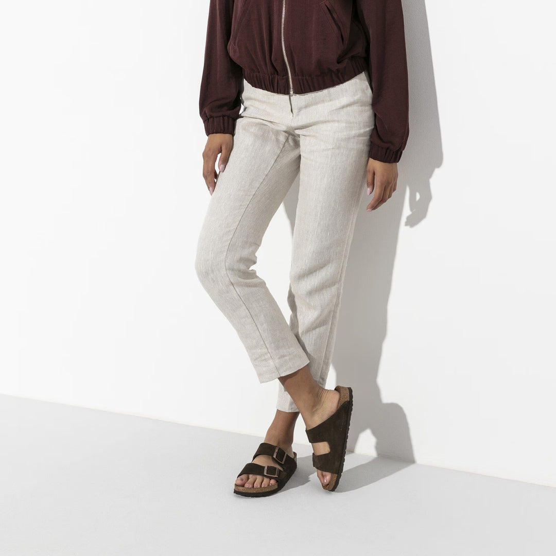 Person wearing a maroon jacket, light gray pants, and black sandals on a white background