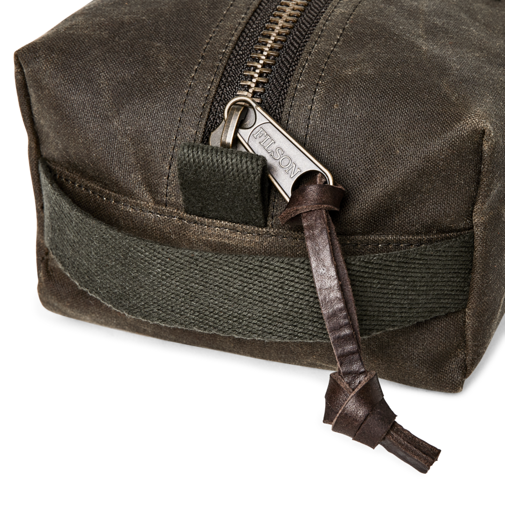 Close-up of a dark brown waxed canvas pouch with a silver-toned metal zipper pull engraved with the brand name 'FALCON'.