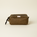 Brown waxed canvas dopp kit with a visible brand label on a white background