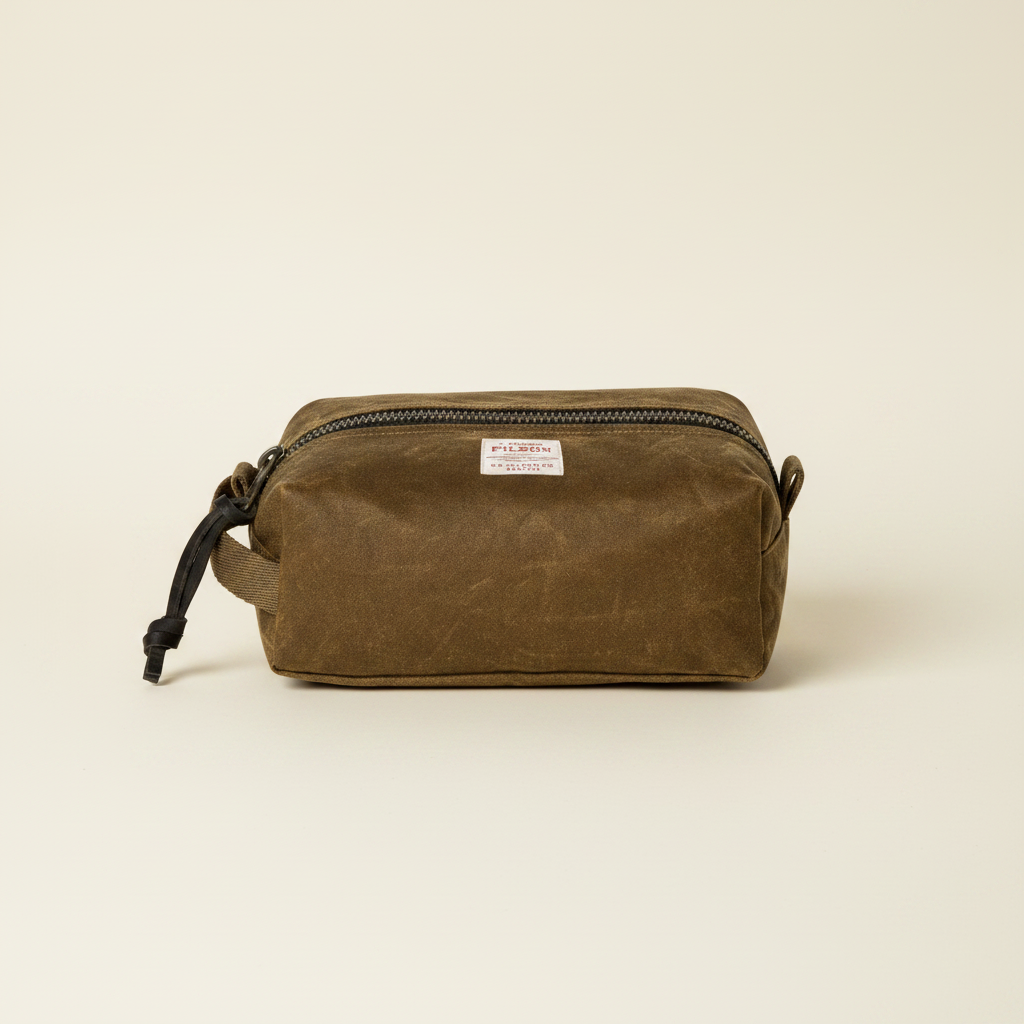 Brown waxed canvas dopp kit with a visible brand label on a white background