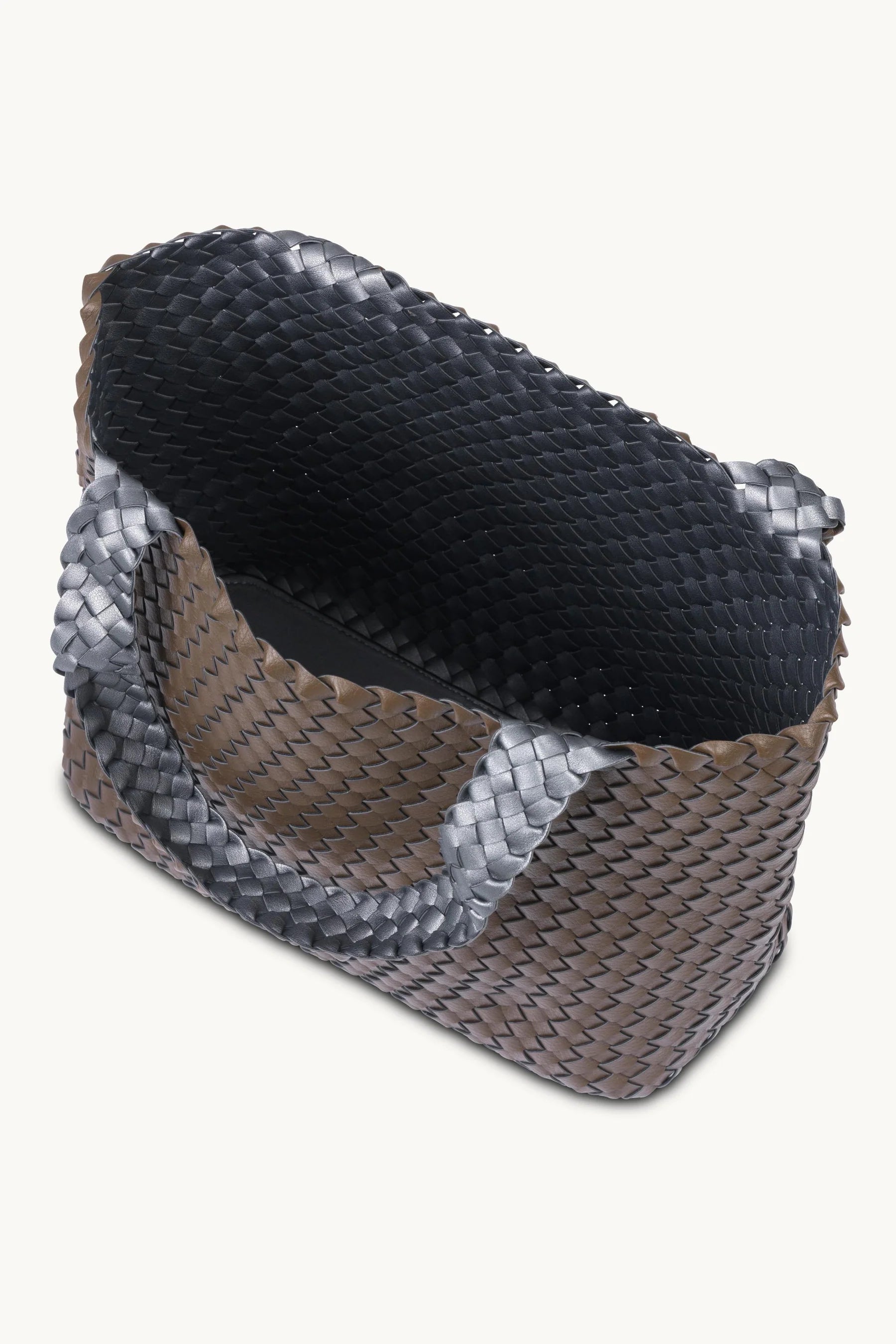 A woven leather clutch bag with a textured basketweave pattern in black and metallic silver, shown from an elevated angle on a light cream background.