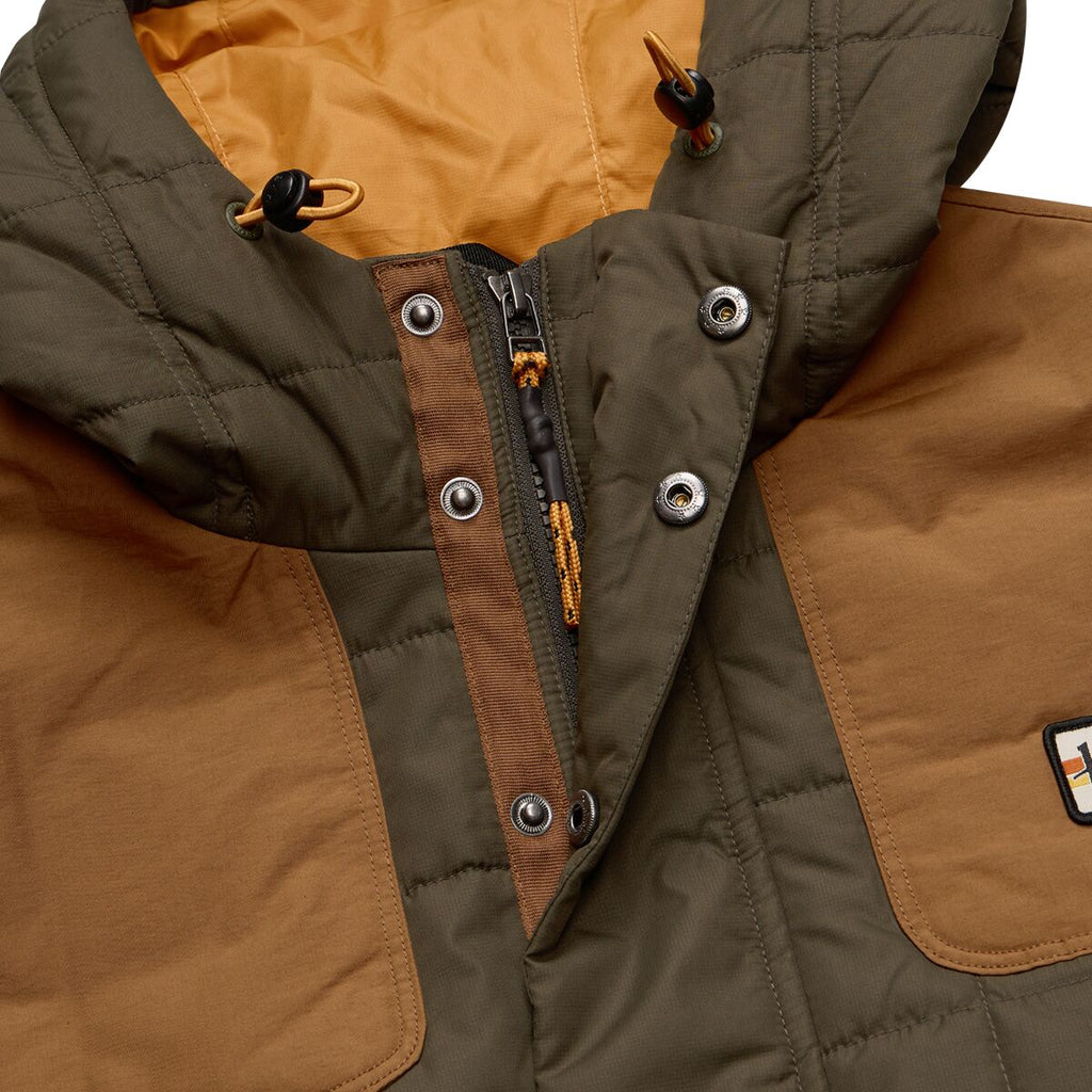 Close-up of a brown and green quilted jacket with a brand logo.
