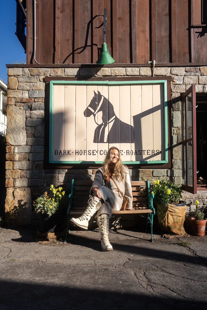 Woman sitting on a bench in front of a building with a large horse logo and text.