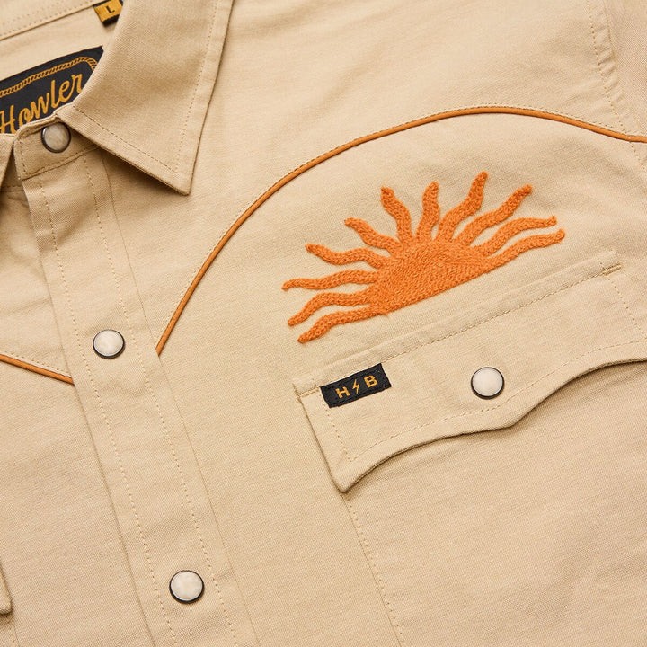 Beige jacket with orange embroidered sun design and 'Howler' branding.