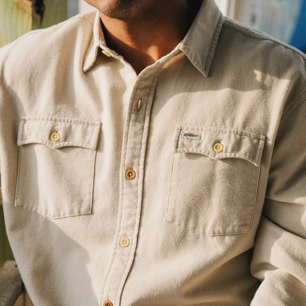 Close-up of a beige shirt with a brand logo on a blurred background