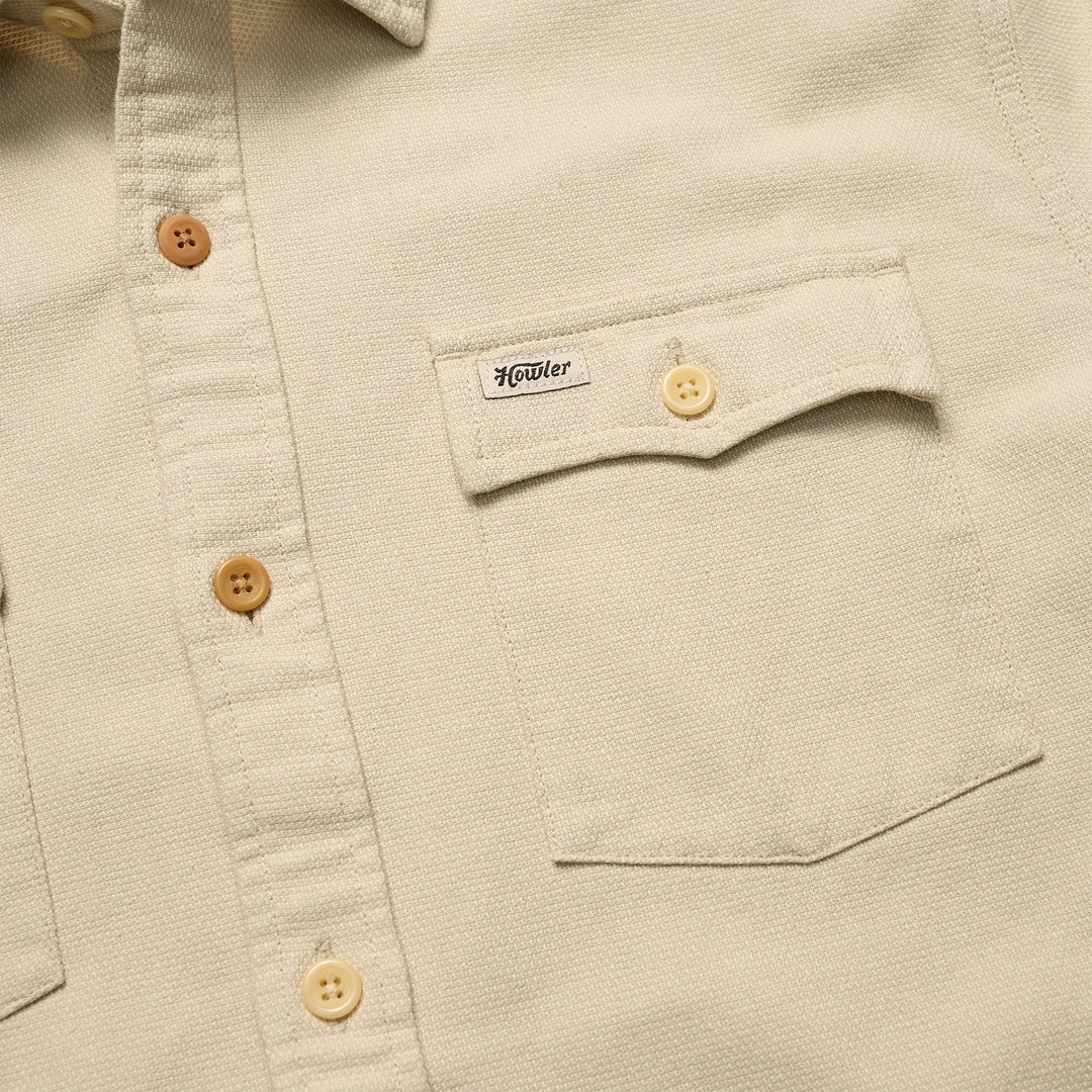 Close-up of a beige shirt with button details and a brand label.
