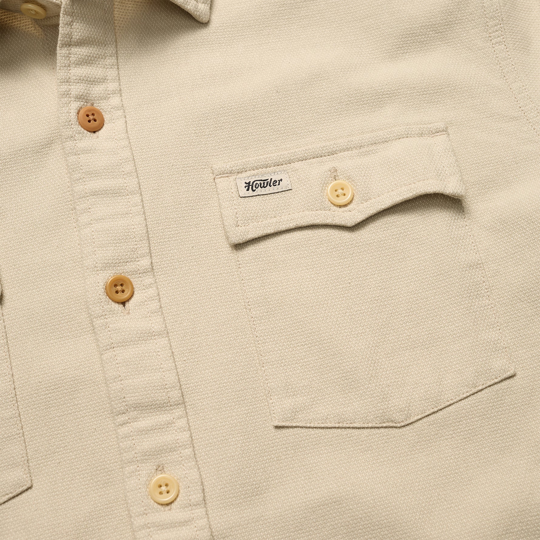 Close-up of a beige shirt with button details and a brand label.