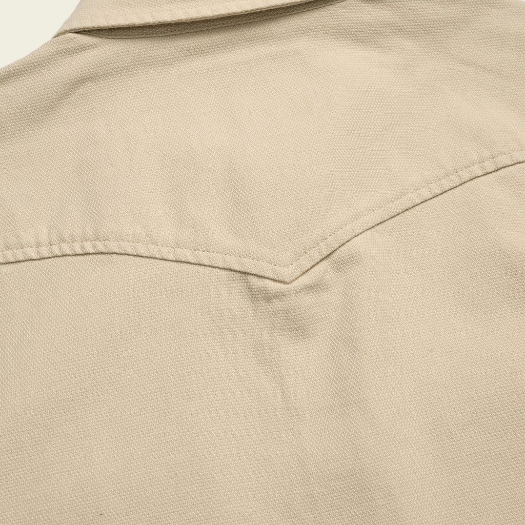Close-up of a beige jacket with a collar and pocket detail.