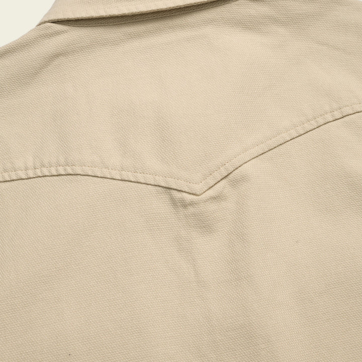 Close-up of a beige jacket with a collar and pocket detail.