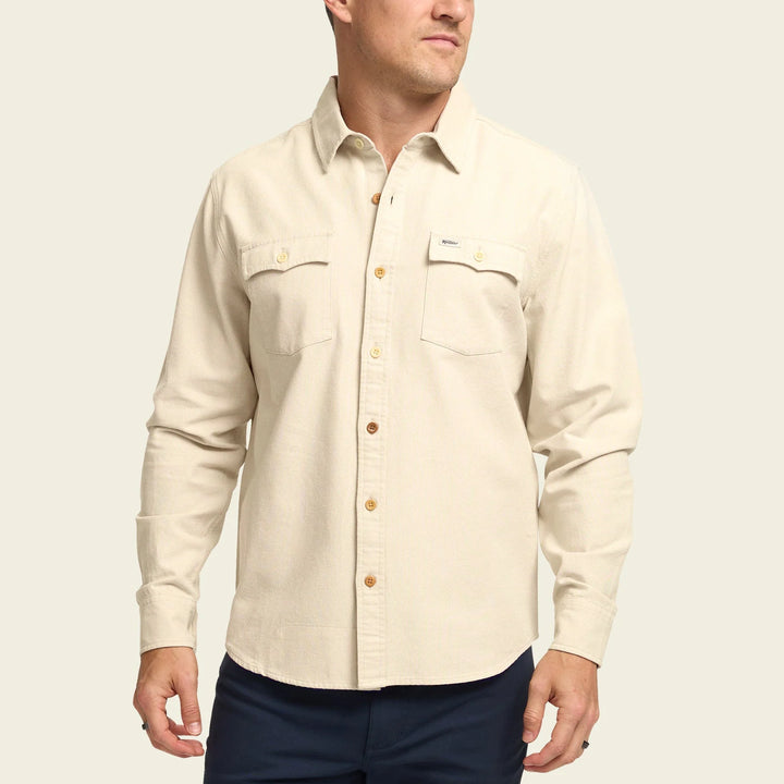 Man wearing a beige button-up shirt with a plain background