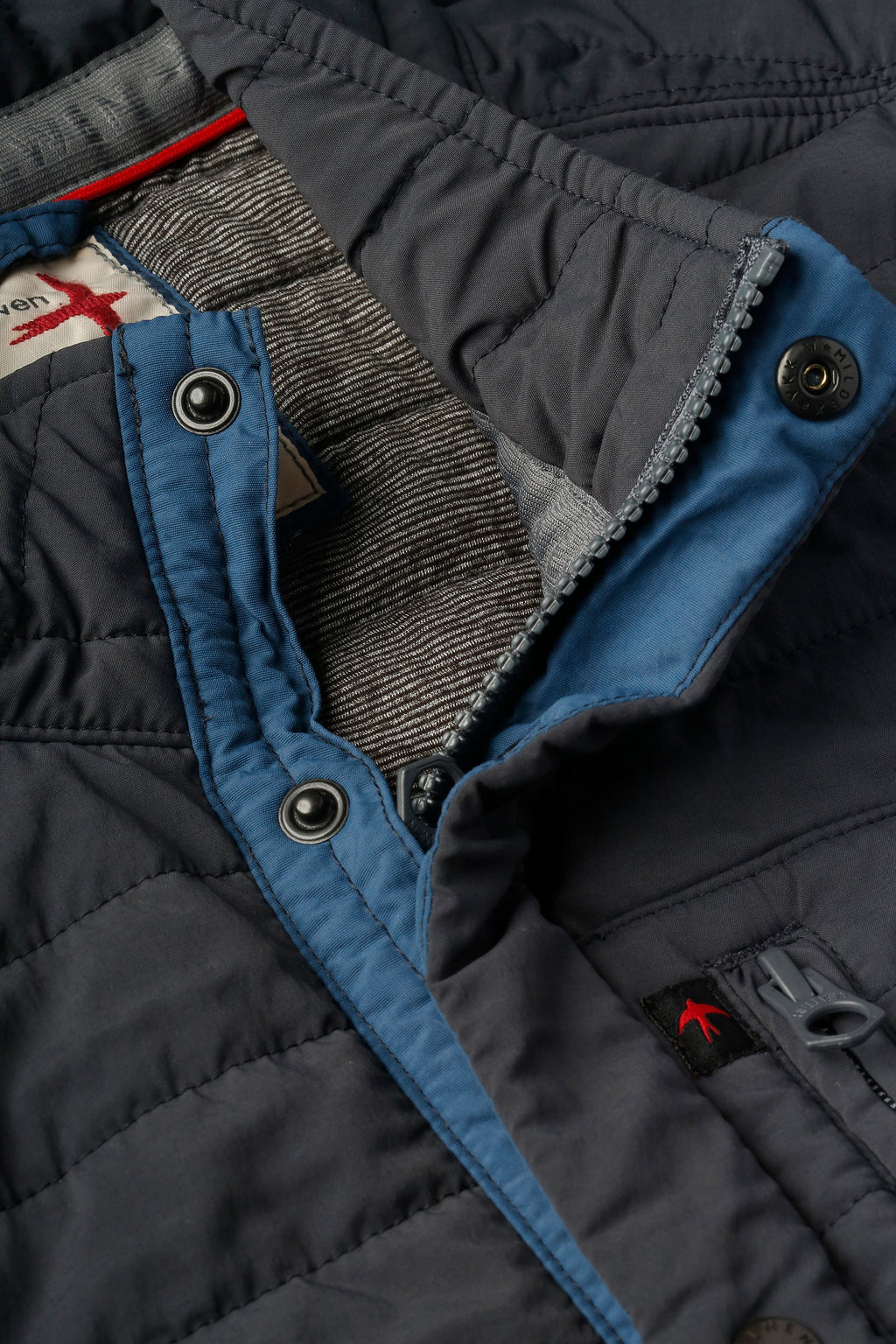 Close-up of a dark jacket with blue lining and visible brand logo.