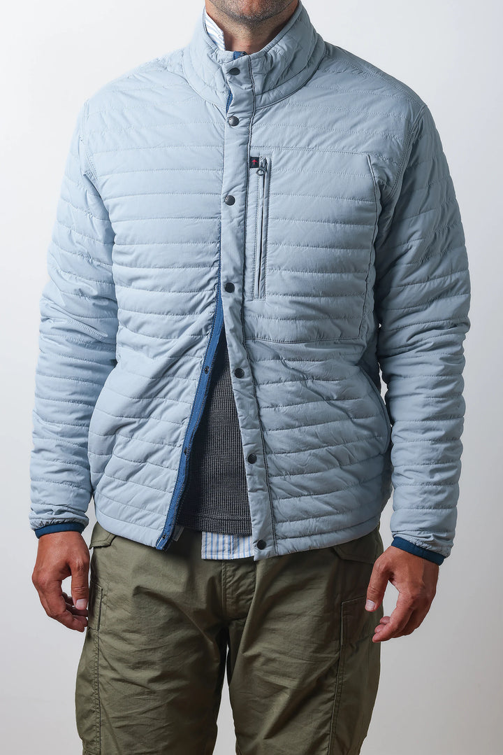 Person wearing a light blue quilted jacket with a plain background
