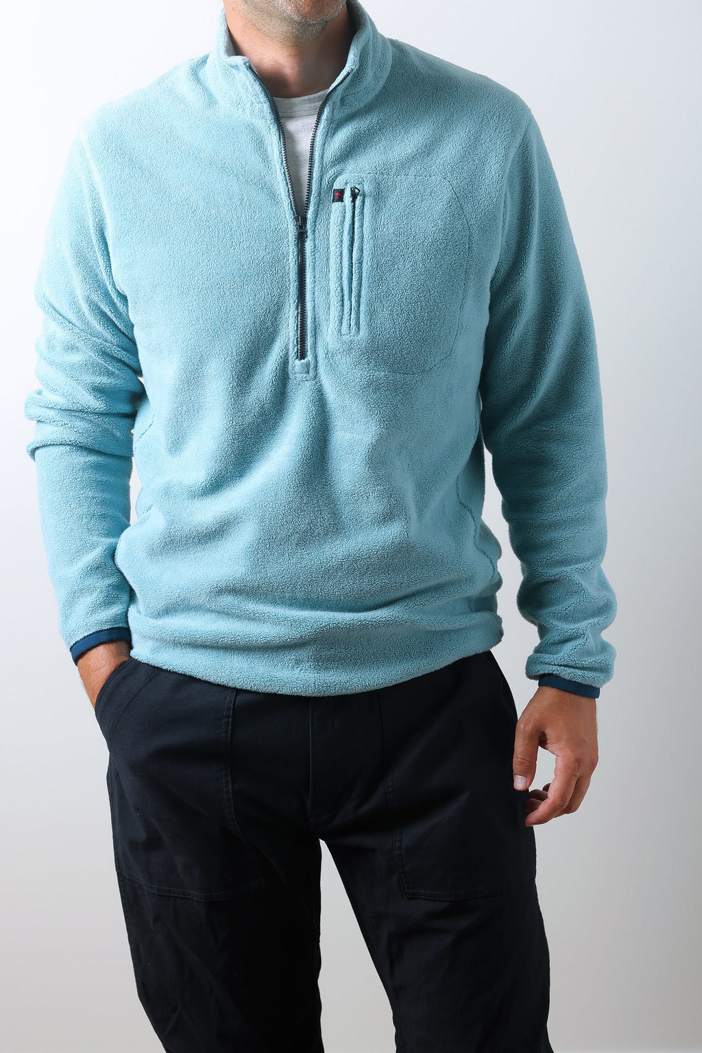 Person wearing a light blue fleece pullover with a zipper on a white background