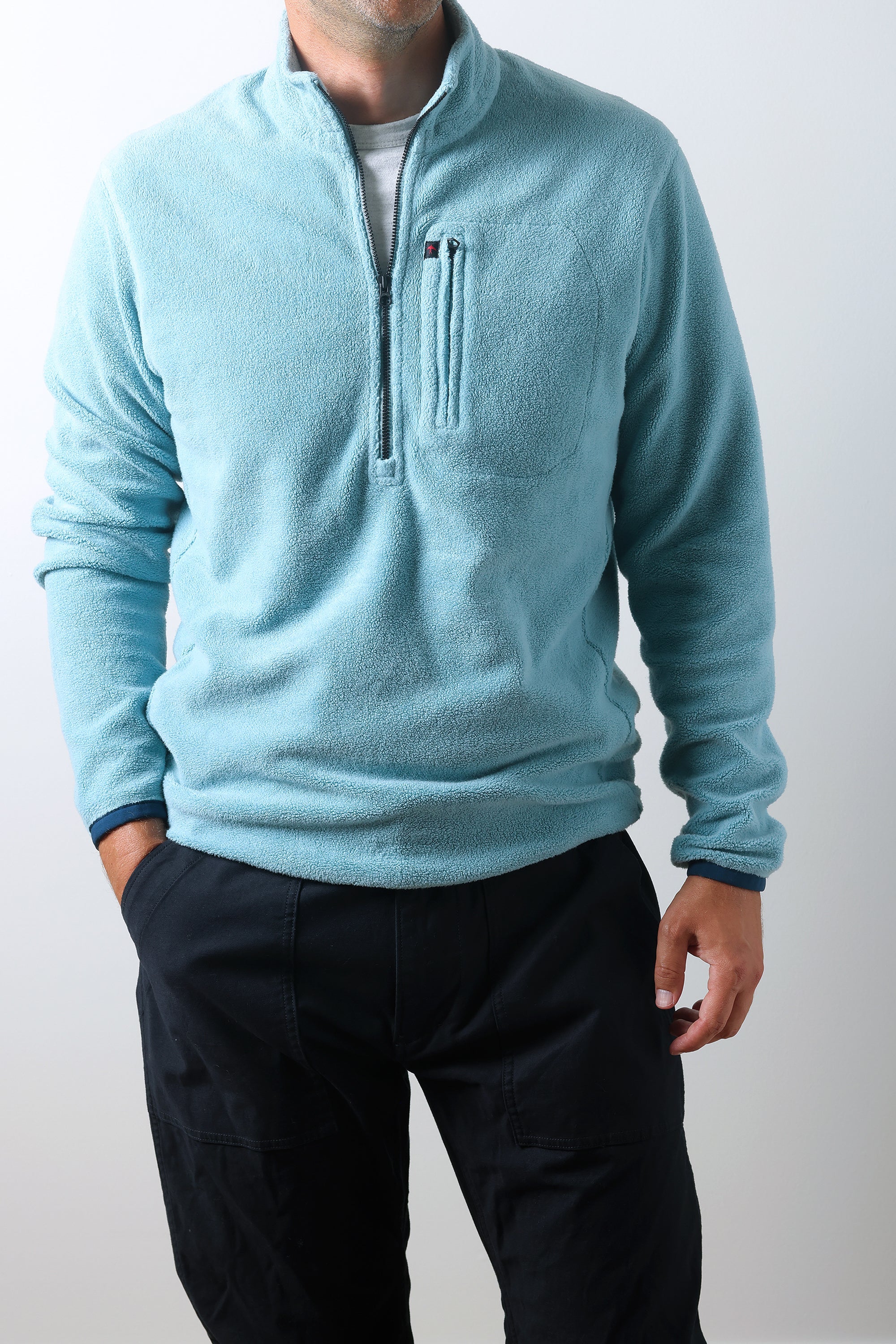 Person wearing a light blue fleece pullover with a zipper on a white background