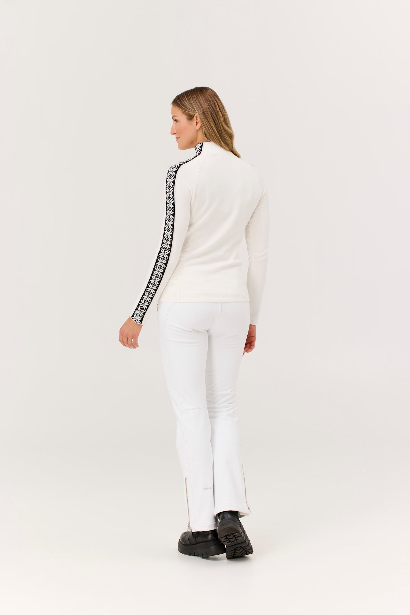 Woman wearing a white outfit with black and white patterned sleeves on a white background