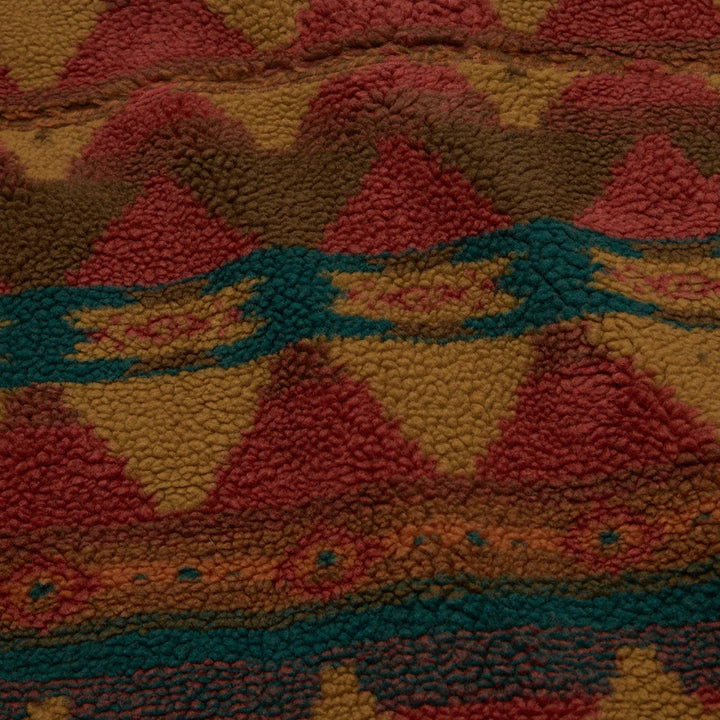Close-up of a textured fabric with geometric pattern in red, orange, and green.