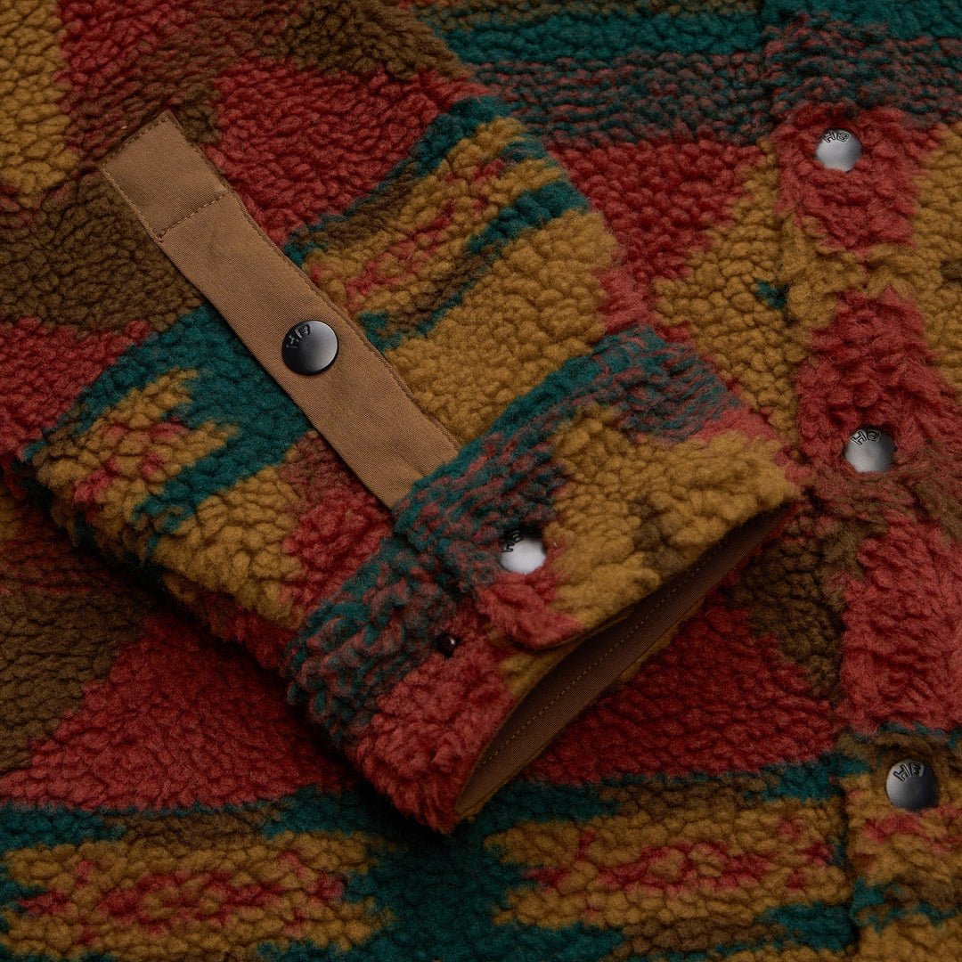 Close-up of a colorful textured fabric with a leather strap and buttons.