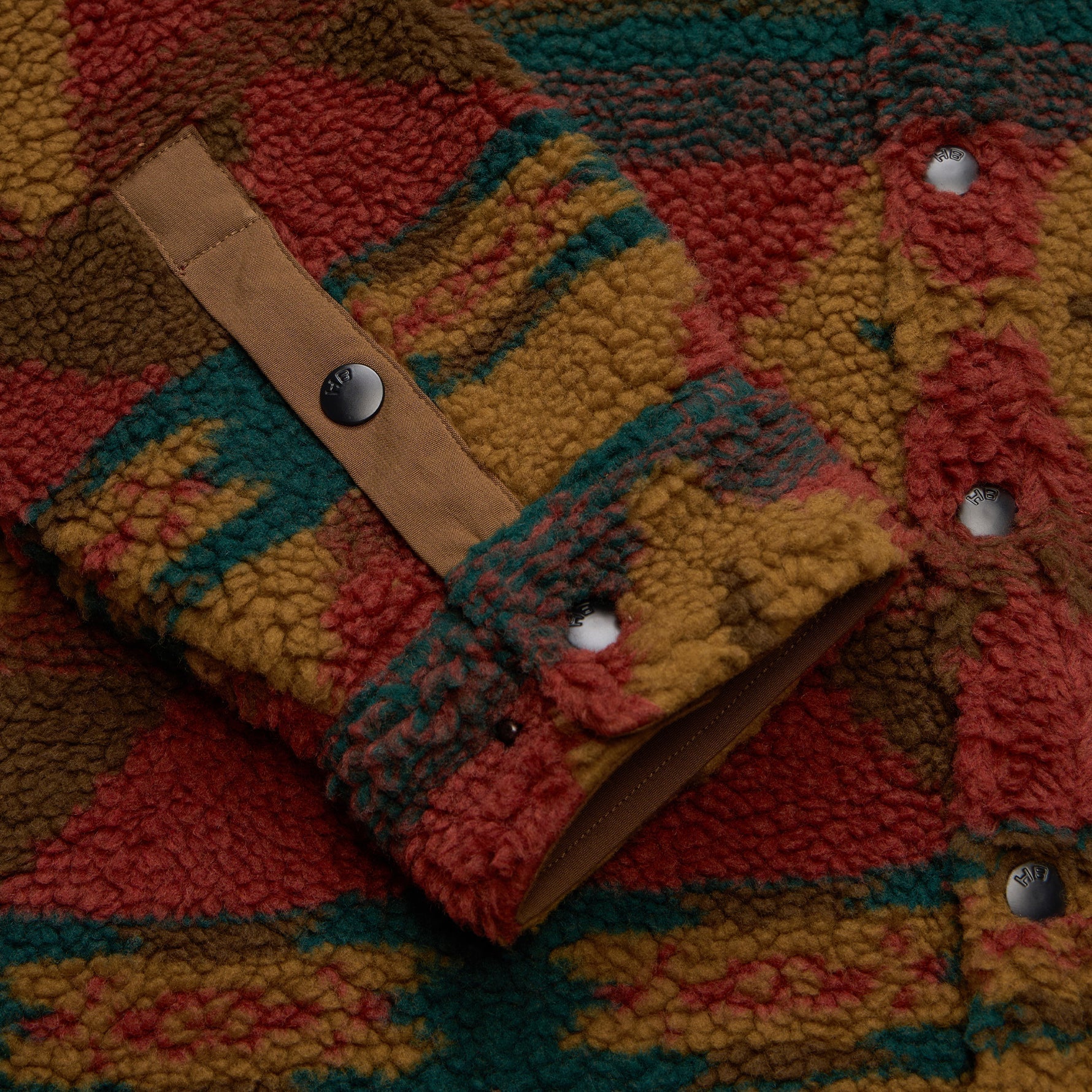 Close-up of a colorful textured fabric with a leather strap and buttons.