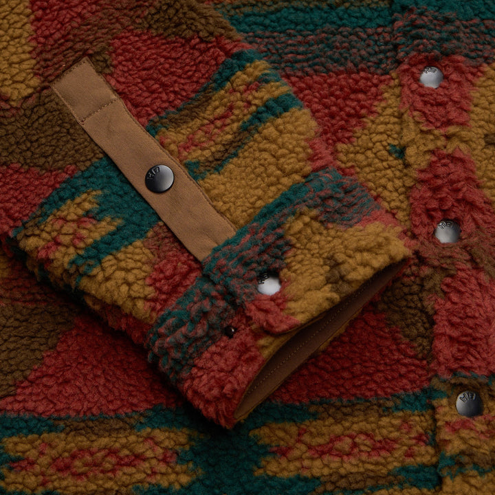 Close-up of a colorful textured fabric with a leather strap and buttons.