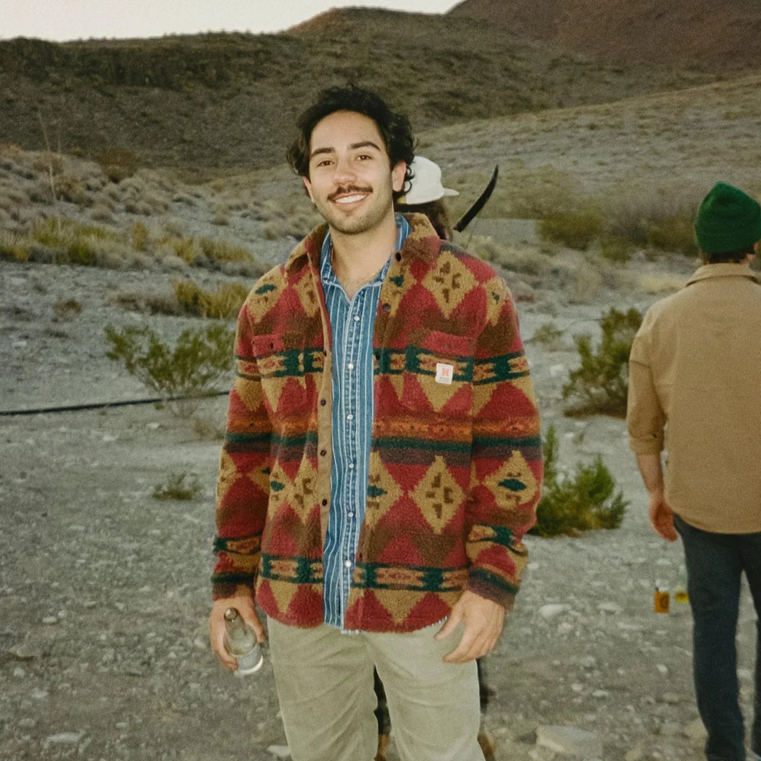 Man wearing a patterned jacket in a desert-like setting