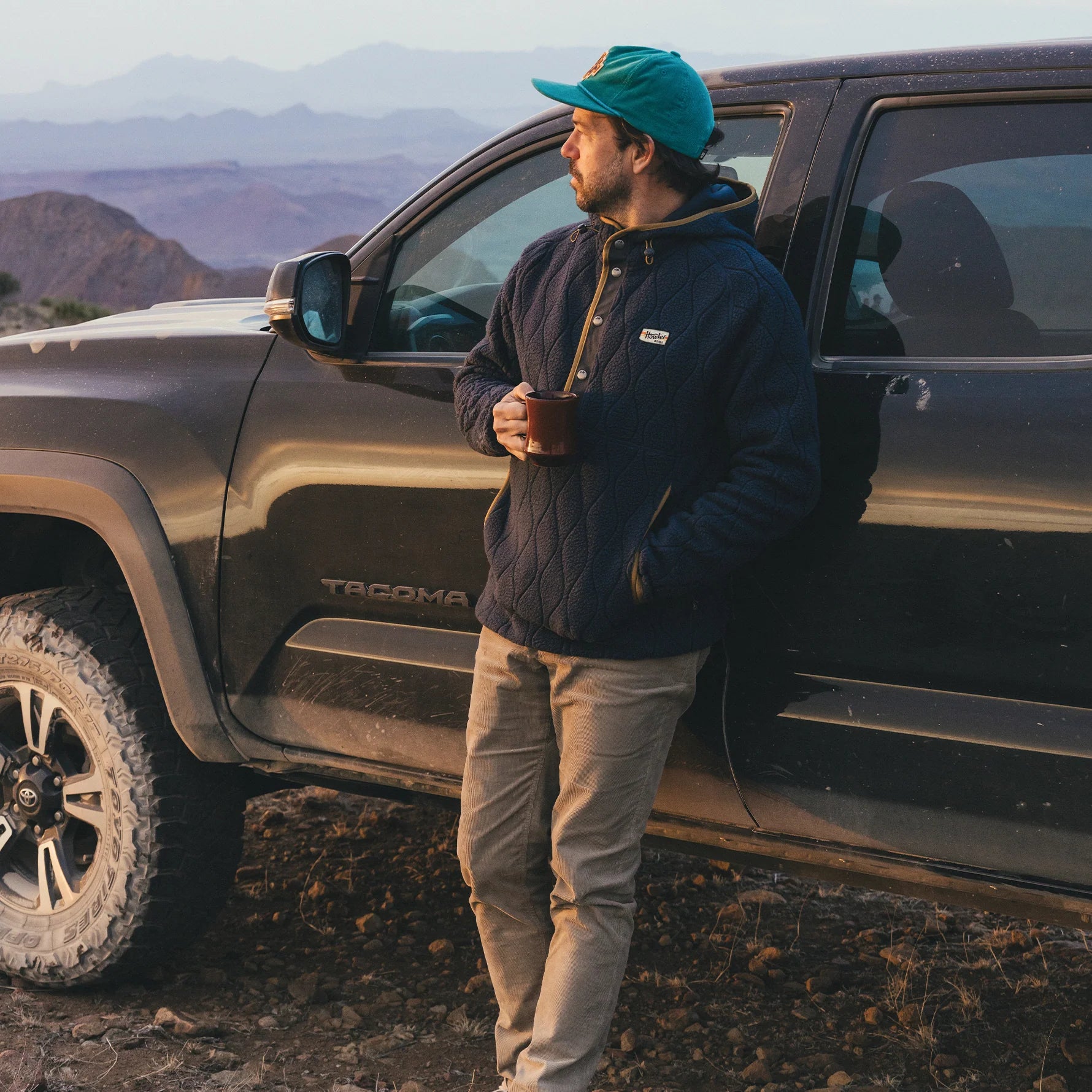 Man standing next to a Toyota Tacoma truck in a mountainous area