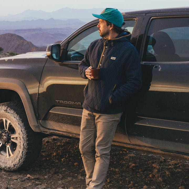 Man standing next to a Toyota Tacoma truck in a mountainous area
