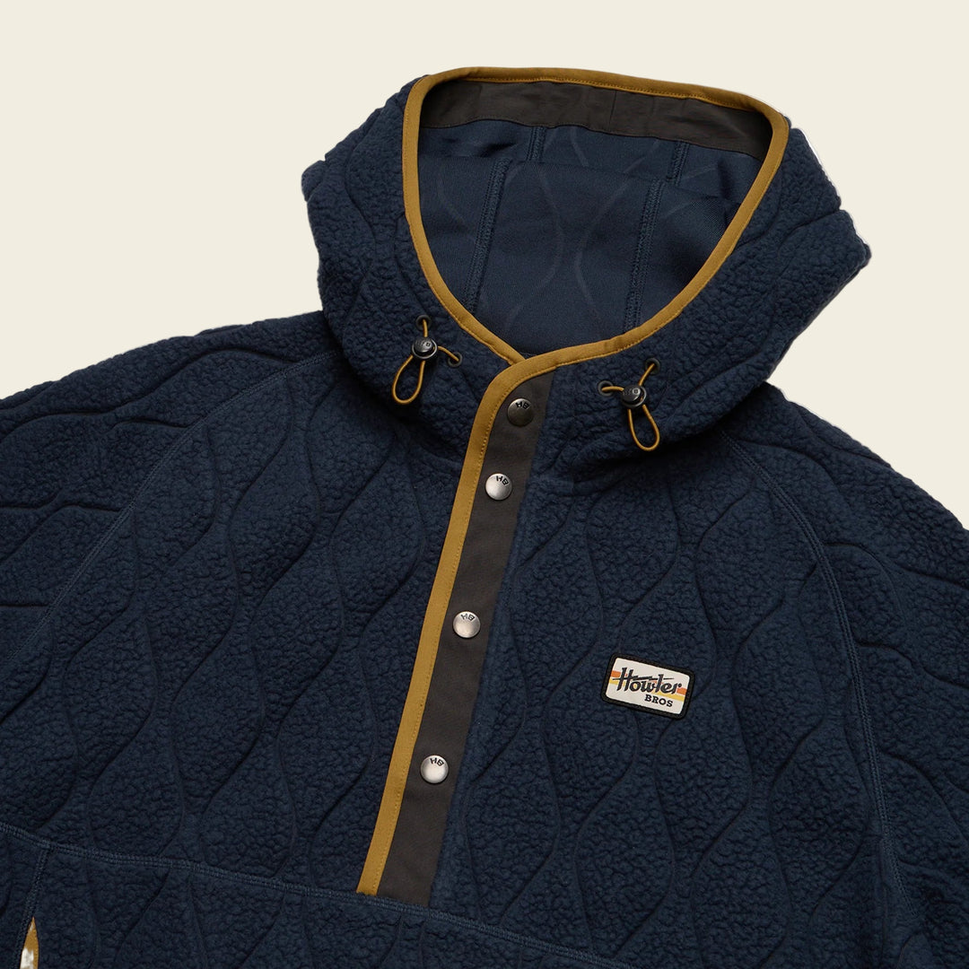 Navy quilted jacket with brown trim and a brand logo on a white background