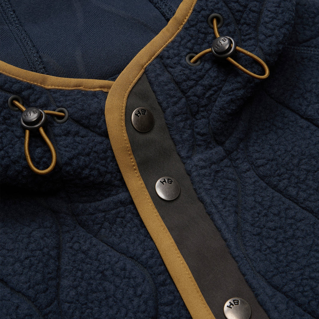 Close-up of a navy blue jacket with brown leather straps and buttons.